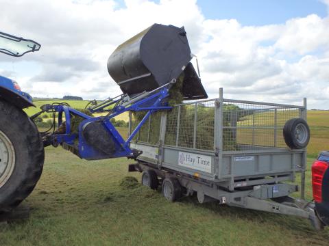 Unloading green hay into trailer